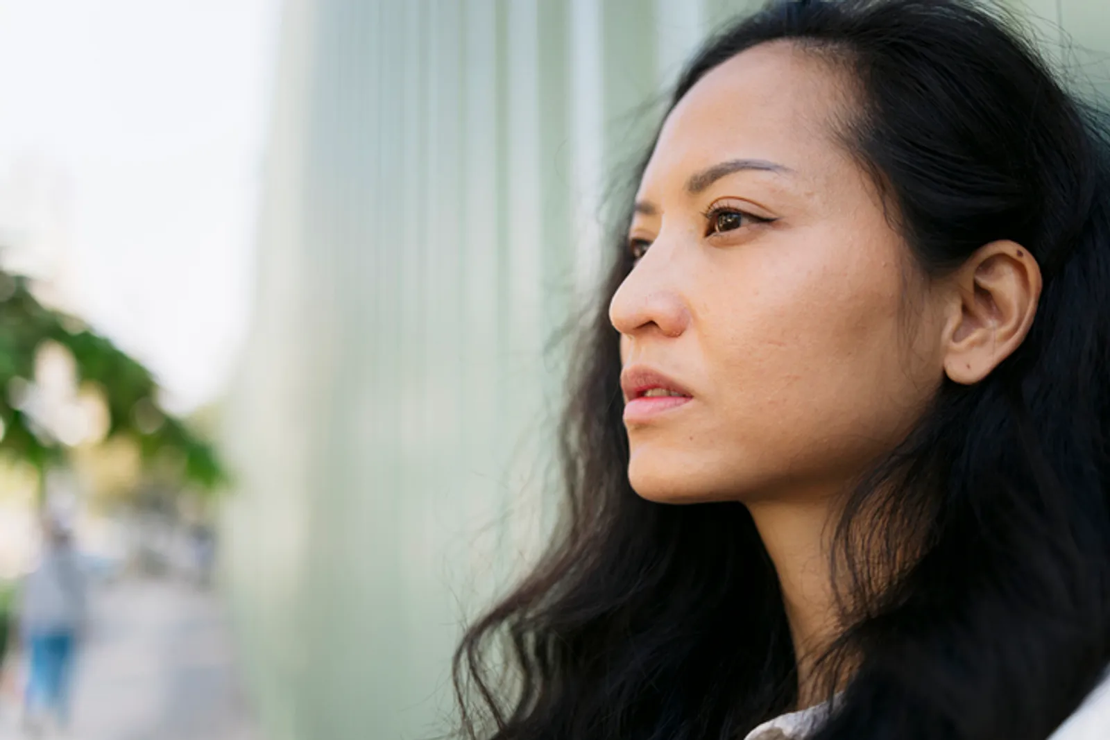Close-up of a young asian woman gazing hopefully into the distance, standing in an urban environment