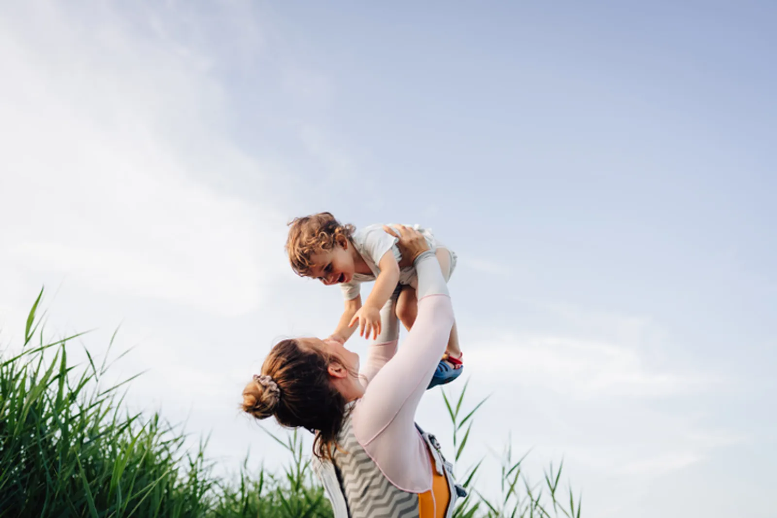 The image captures a heartwarming moment between a woman and a young child. The woman is holding the child up in the air, giving the child a gentle.