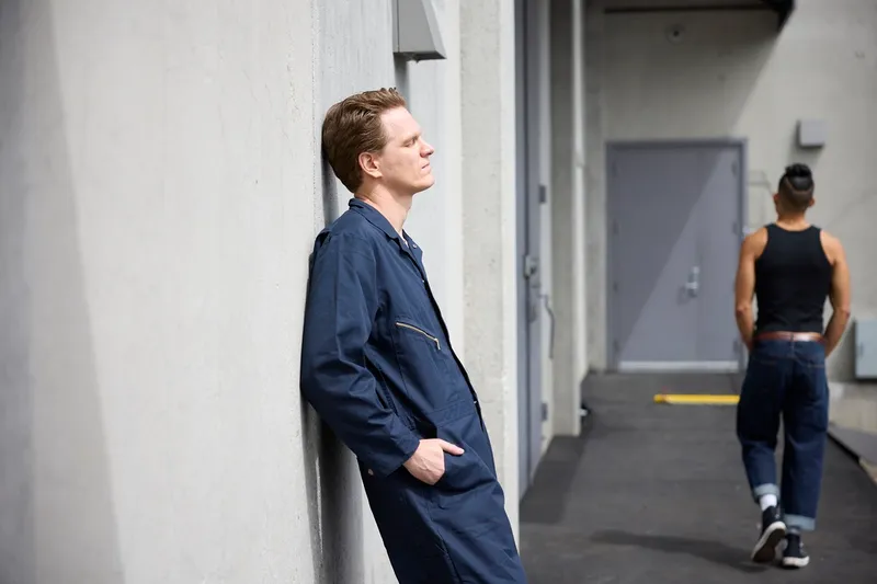 a man leans against a wall