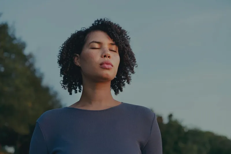 a woman standing with her eyes closed