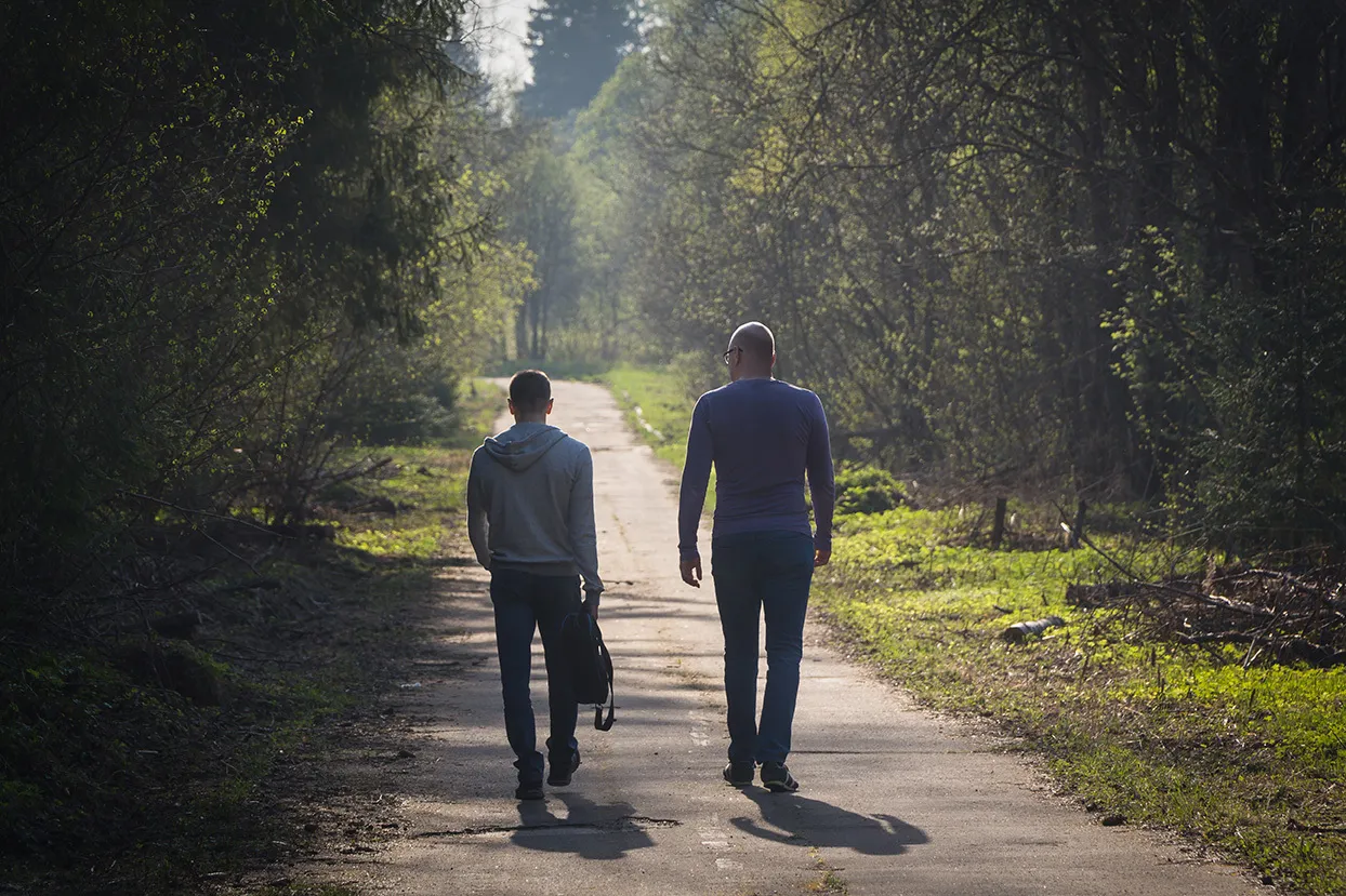 Two people walking outside on a trail
