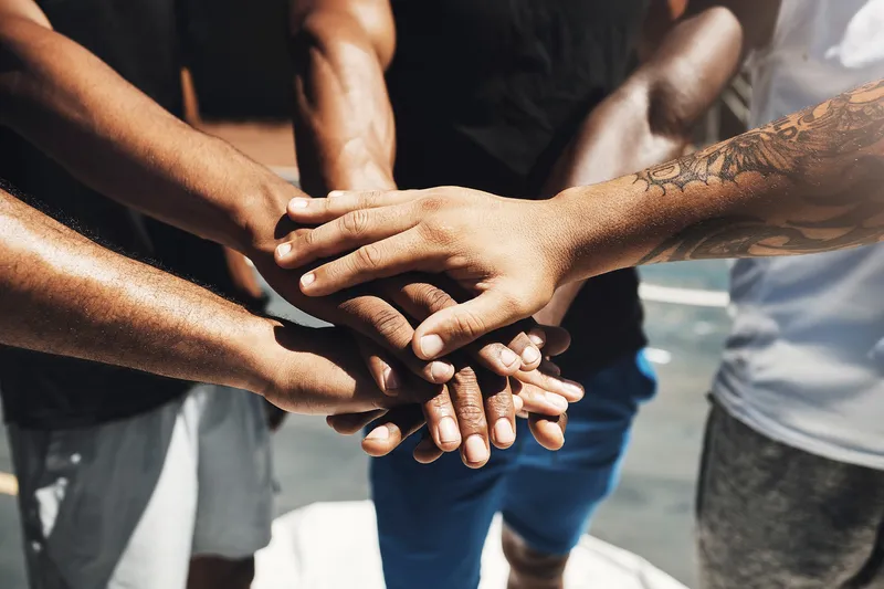 Group of people’s hands on top of one another in unison